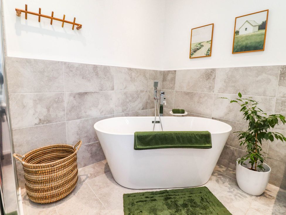 A bathroom with a bathtub and plant at The Swallows near Glasson