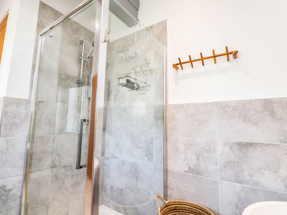 A shower enclosure with a tiled wall and hook rack at The Swallows near Glasson