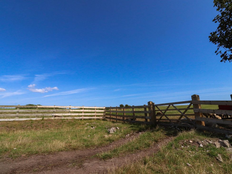 A fenced area with grass and a clear sky at The Swallows near Glasson
