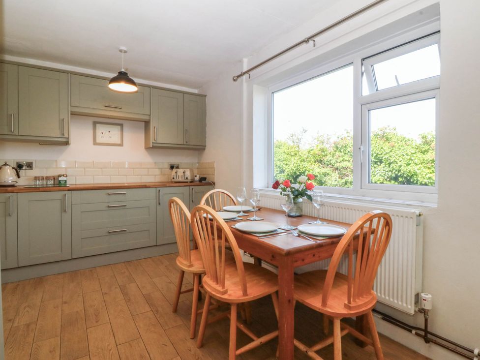 A kitchen with cabinets, a table and chairs at Wilpol in Llanerchymedd
