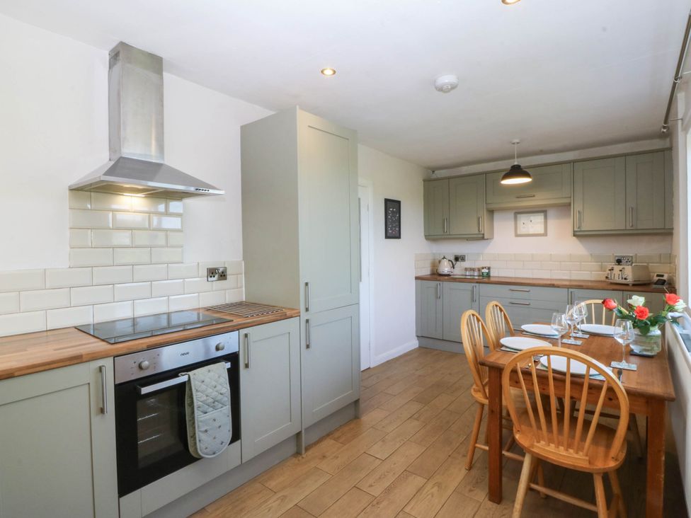 A kitchen with appliances and dining table at Wilpol in Llanerchymedd