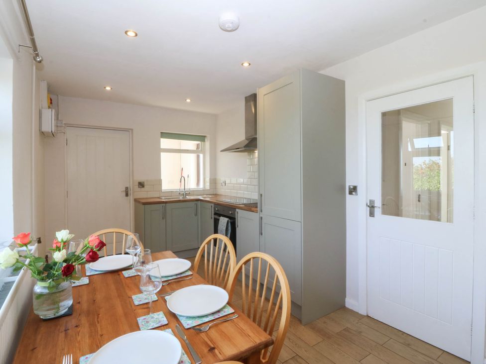 A kitchen with a dining table and chairs at Wilpol in Llanerchymedd