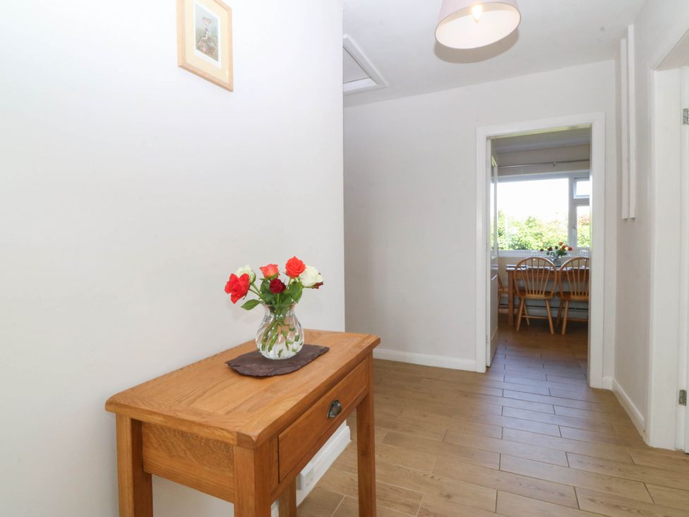 A hallway with a table and flowers at Wilpol in Llanerchymedd