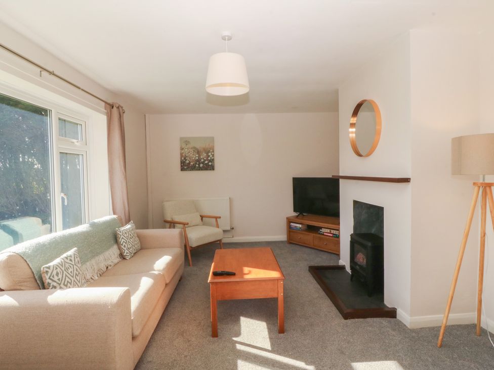 A living room with a sofa, coffee table, and television at Wilpol in Llanerchymedd