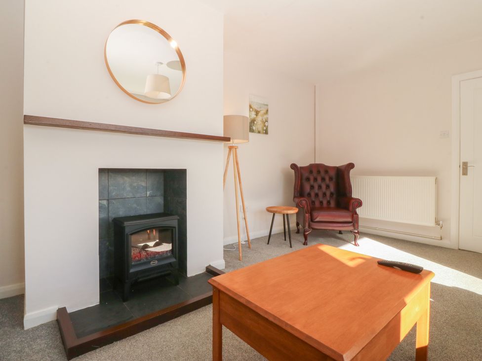 A living room with a fireplace and seating area at Wilpol in Llanerchymedd