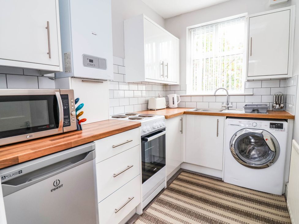 A kitchen with appliances including a microwave and washing machine at 29 Vale Road in Ellesmere Port