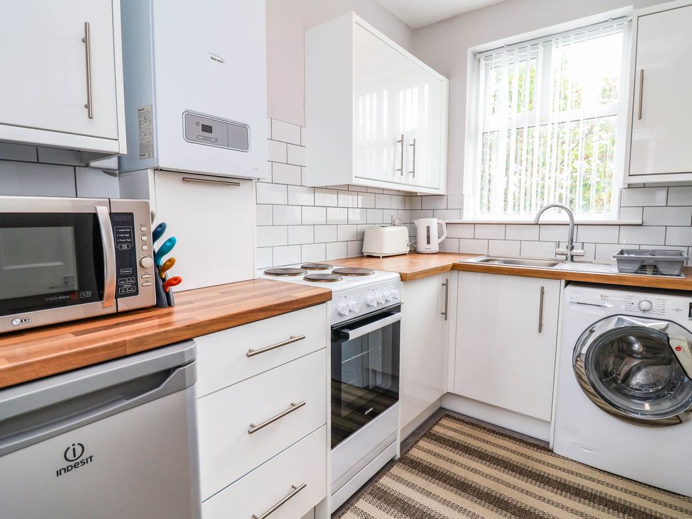A kitchen with appliances including a microwave and oven at 29 Vale Road in Ellesmere Port