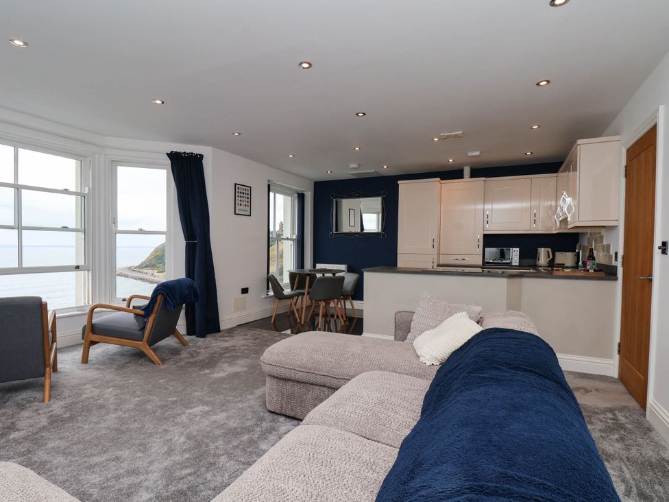 A living room with windows and a kitchen unit at The Gulls Rest in 
