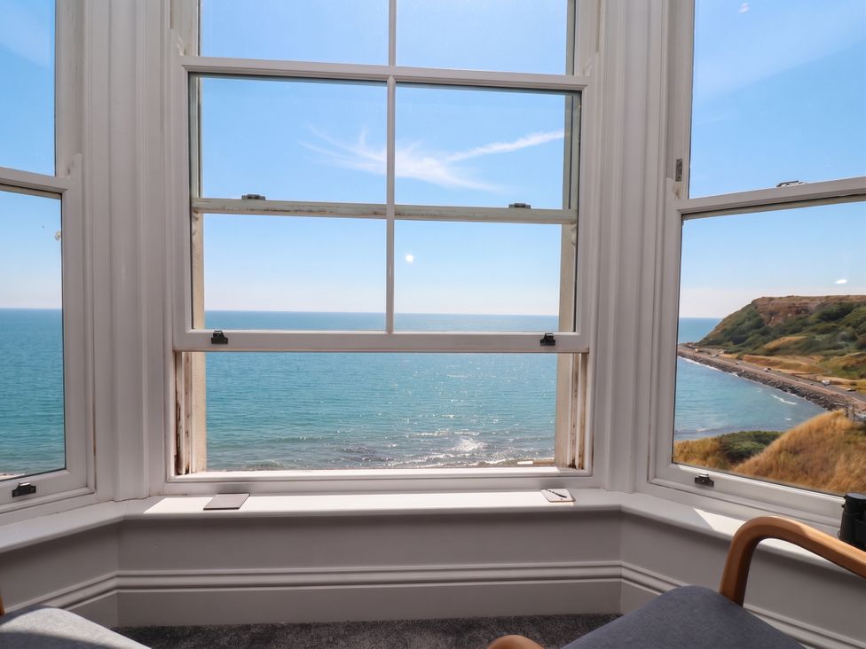 A view of the ocean and hills from a window in a living room at The Gulls Rest