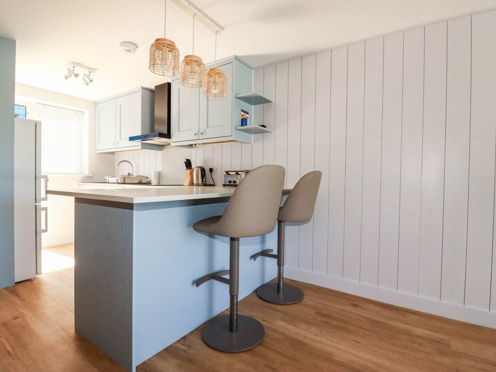 A kitchen with a counter and bar stools at 9 Tides Reach Wadebridge