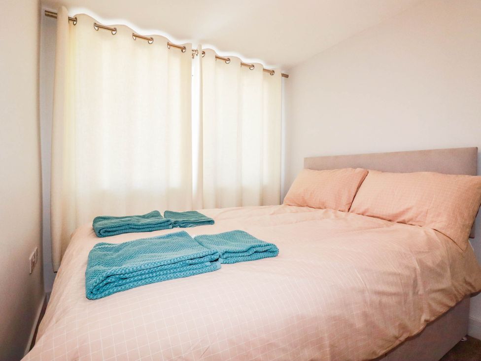 A bedroom with a bed and towels at 9 Tides Reach in Wadebridge