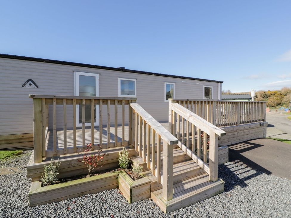 An outdoor view of a wooden deck leading to a door at Dunskey Way in Portpatrick
