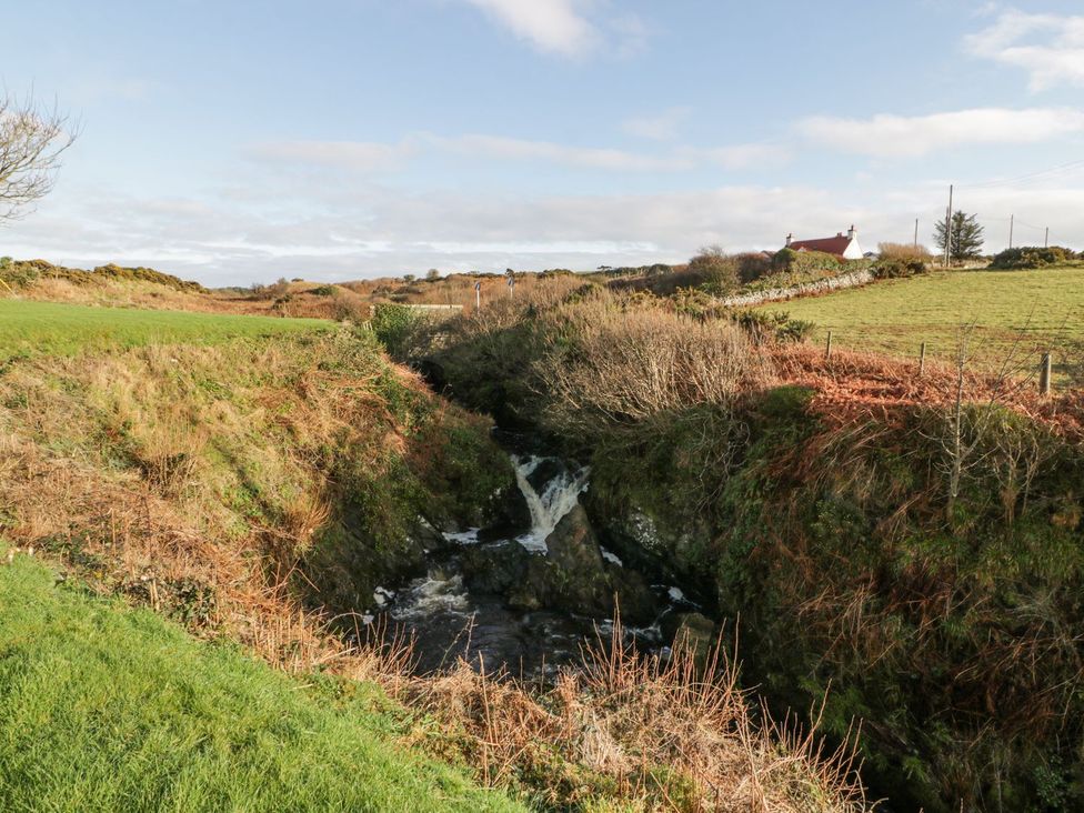 A waterfall with a house in the background at Dunskey Way in Portpatrick