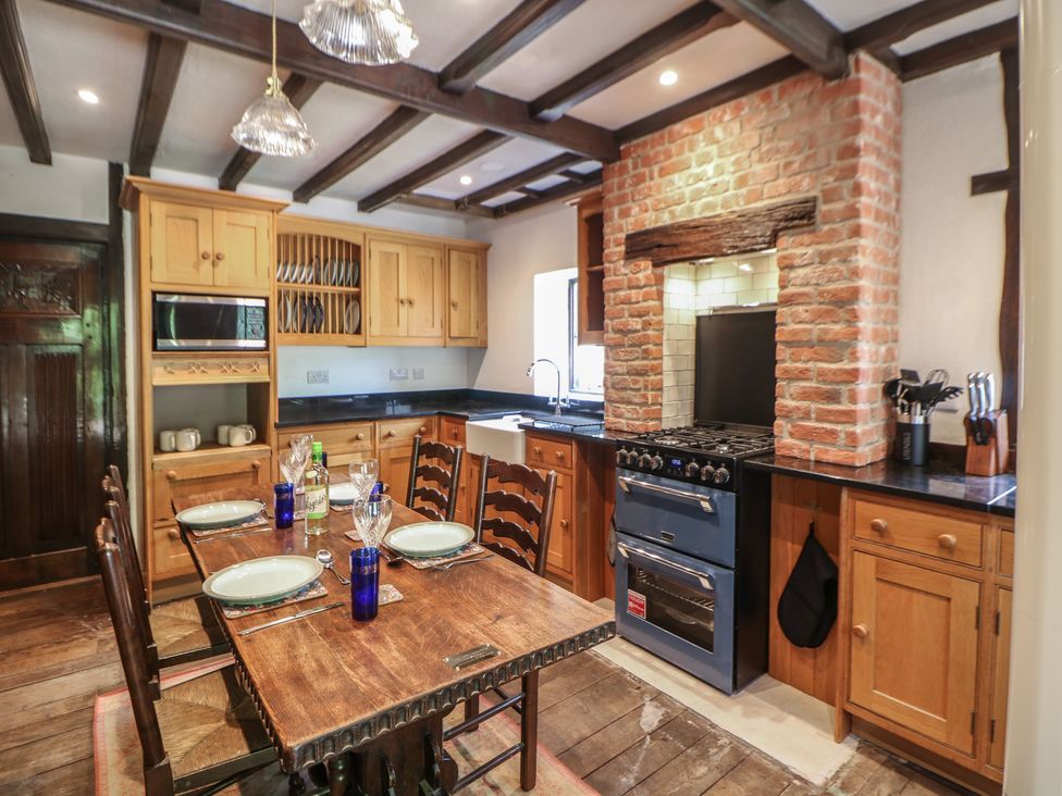 A kitchen with dining table and wooden cabinets at Tudor Lodge near Belper