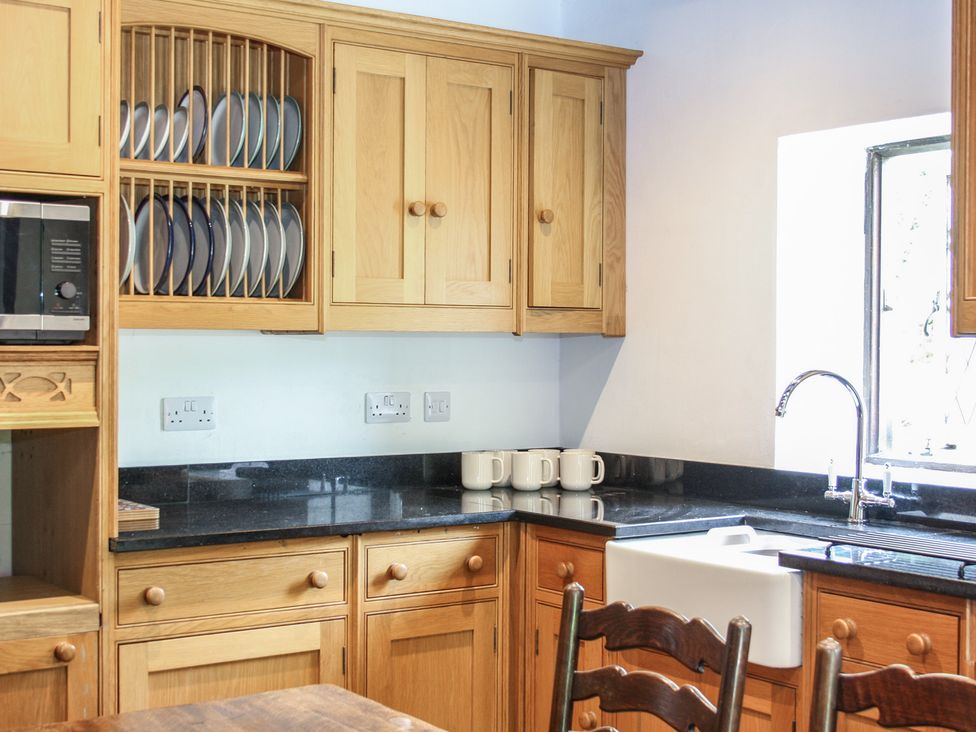 A kitchen with cabinets, plates, mugs, and a sink at Tudor Lodge near Belper