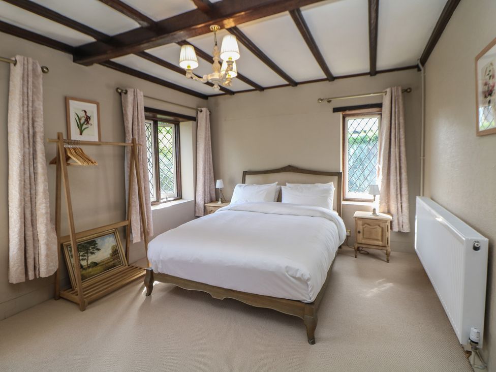 A bedroom with a bed and windows at Tudor Lodge near Belper