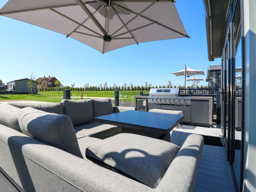 An outdoor patio with a sofa and grill at Lakewood Plot 3 St. Osyth