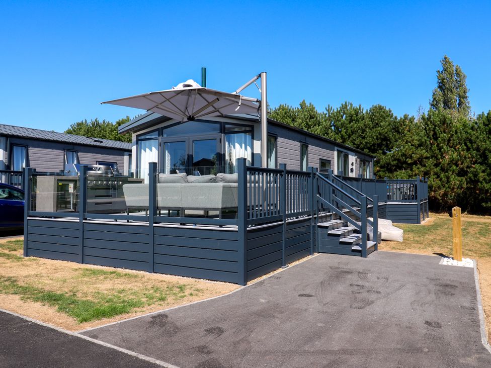 An outdoor area with a sofa and umbrella at Lakewood Plot 5 St. Osyth