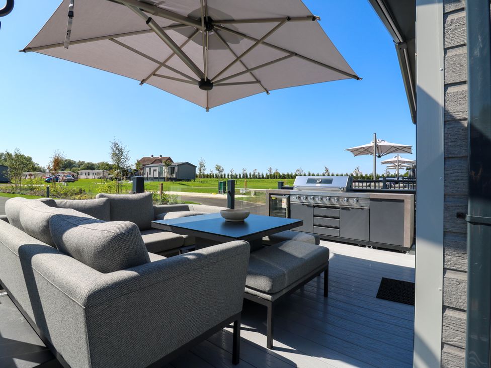 An outdoor patio with a sofa, table, and grill at Lakewood Plot 5 in St. Osyth