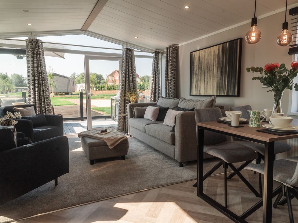 A living room with a sofa and dining area at Lakewood Plot 5 St. Osyth