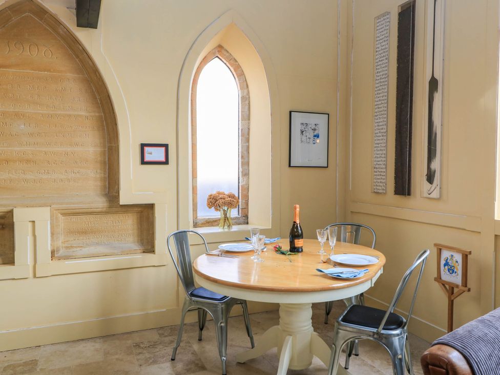 A dining room with a round table and wine setup at The Sunday School Room in Sherborne