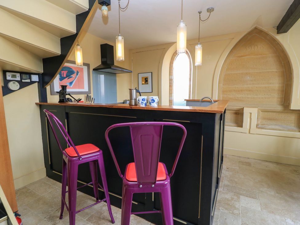 A kitchen with a counter and stools at The Sunday School Room in Sherborne