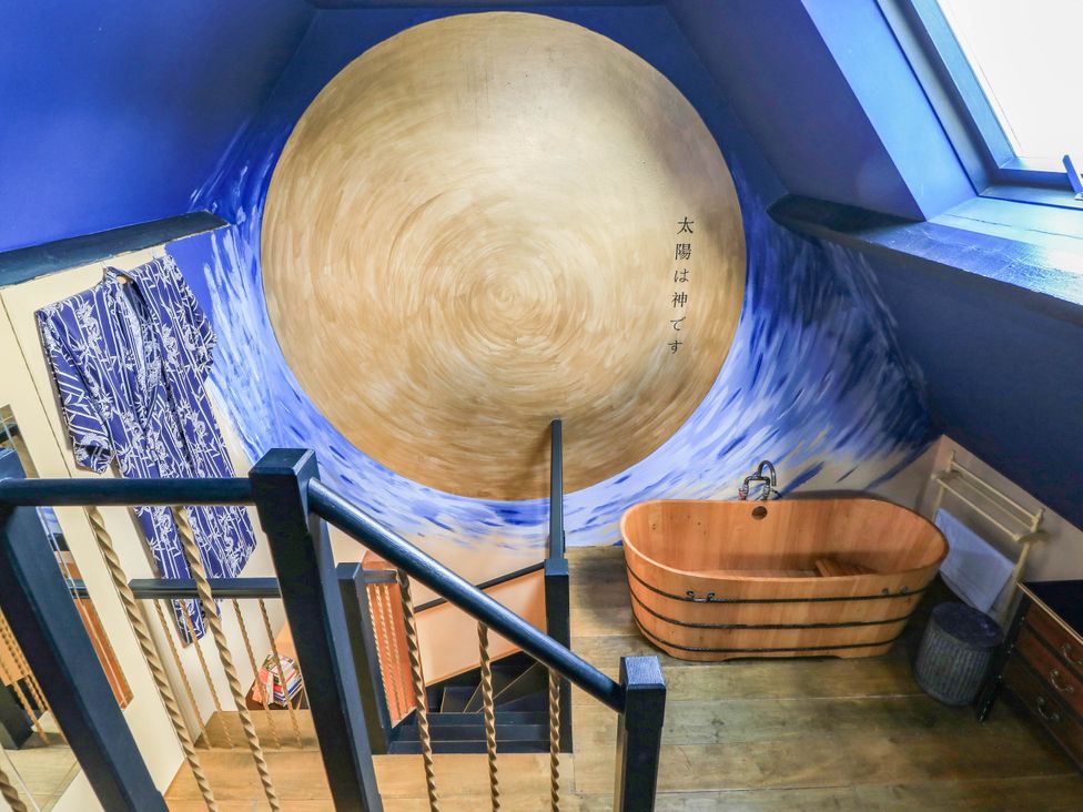 A bathroom with a wooden bathtub and blue wall mural at The Sunday School Room in Sherborne
