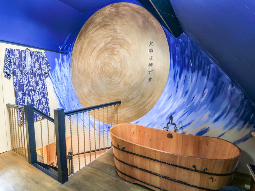 A bathroom with a wooden bath tub and wall art at The Sunday School Room in Sherborne