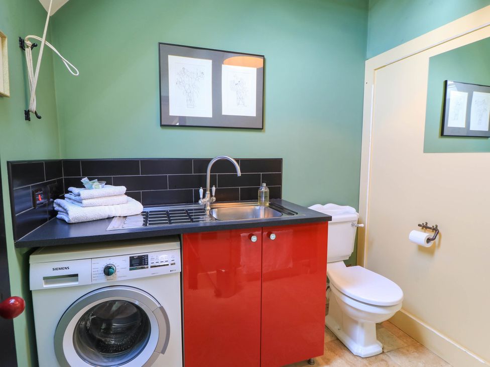 A laundry room with a washing machine and sink at The Sunday School Room in Sherborne