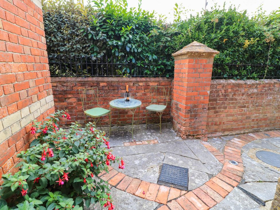 An outdoor area with a table and chairs beside a flower bush at The Sunday School Room Sherborne