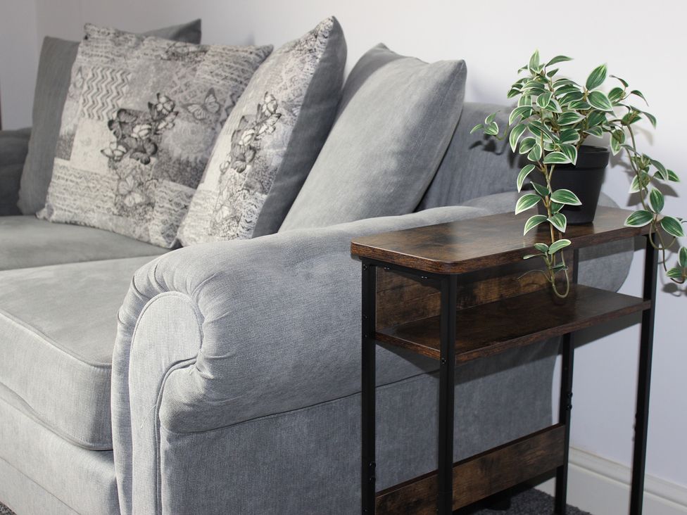 A sofa with decorative cushions and a side table with a plant at Oliver Wests Apartment 1 in Scarborough