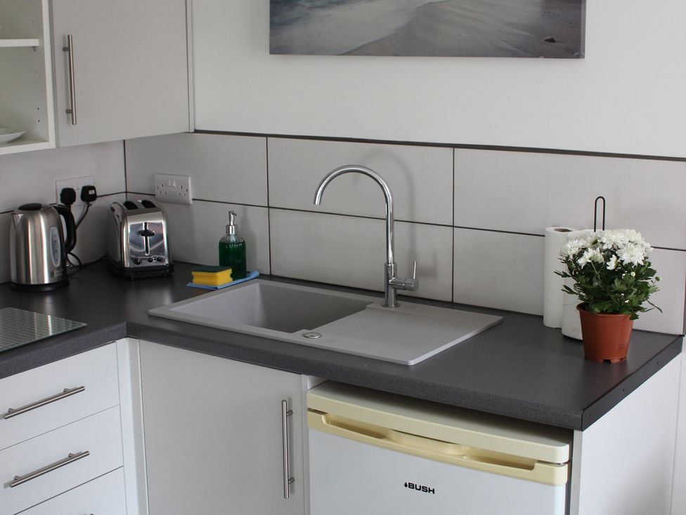 A kitchen with a sink and kitchen appliances at Oliver Wests Apartment 1 Scarborough