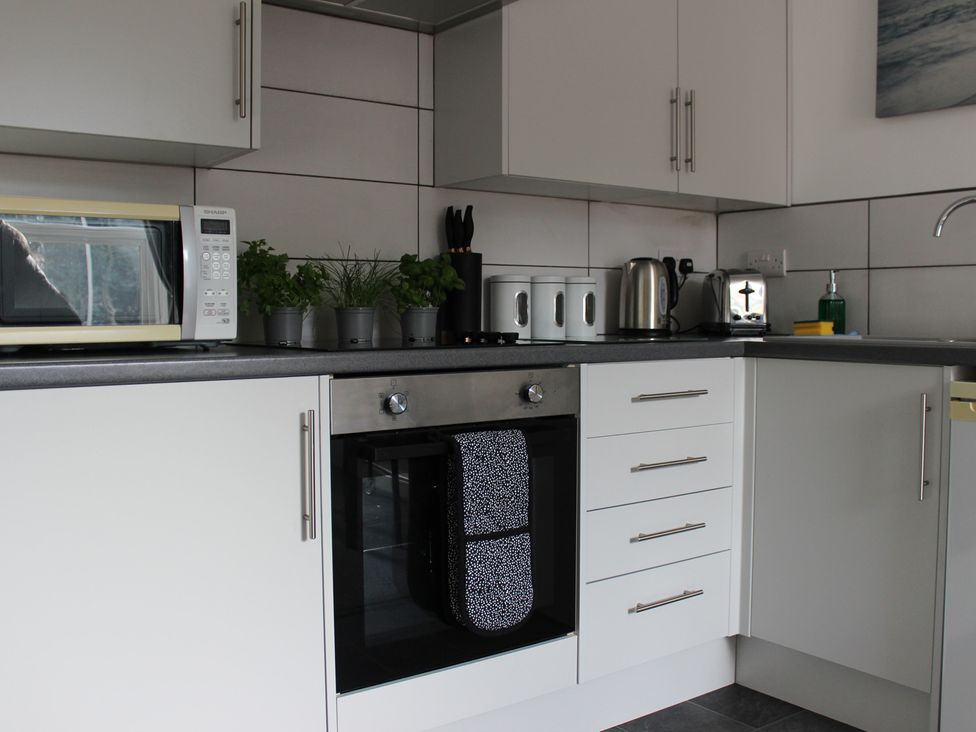 A kitchen with a microwave, oven, and potted plants at Oliver Wests Apartment 1 in Scarborough