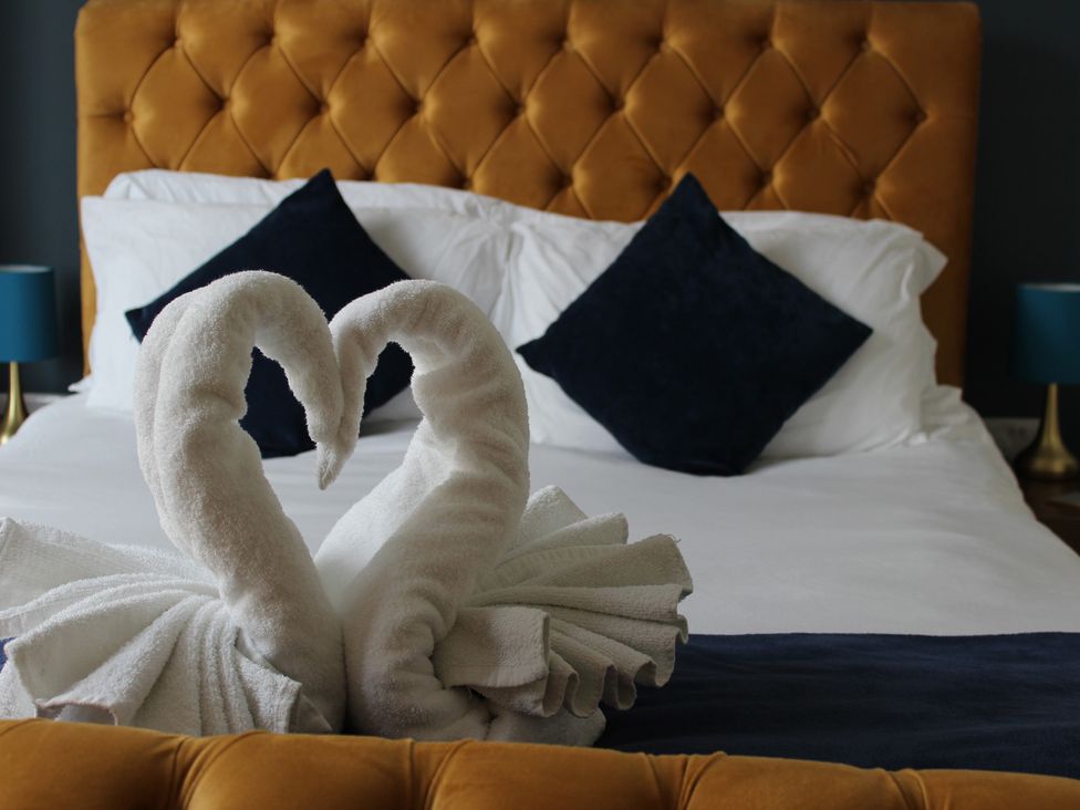 A bedroom with a bed featuring towel swans and decorative cushions at Oliver Wests Apartment 1, Scarborough
