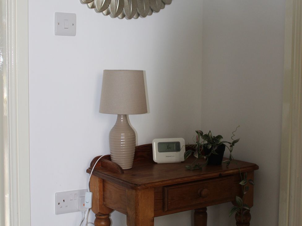 A table with a lamp and clock in a hallway at Oliver Wests Apartment 1 in Scarborough