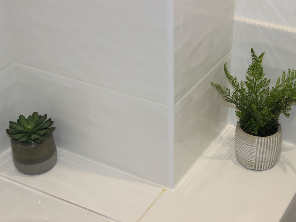 A bathroom corner with two potted plants and tiled wall at Oliver Wests Apartment 1 in Scarborough