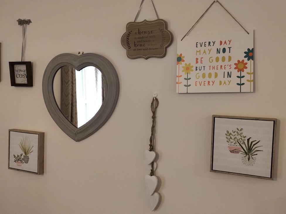 A living room wall with a heart-shaped mirror and decorative wall art at Oliver Wests Apartment 4 in Scarborough