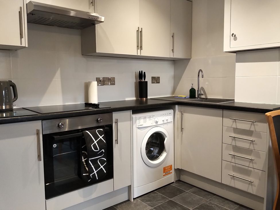 A kitchen with a washing machine, oven, and sink at Oliver Wests Apartment 4 Scarborough