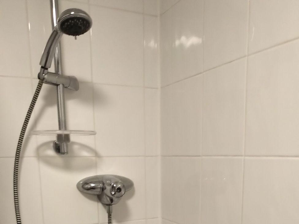 A shower setup with a showerhead and control in Oliver Wests Apartment 4 Scarborough