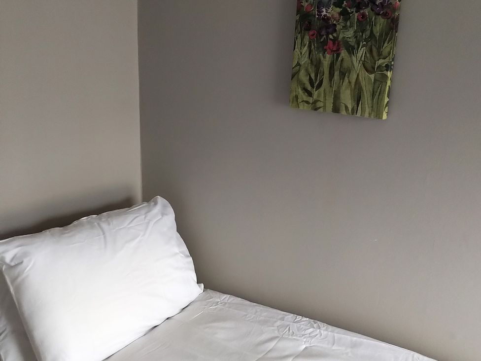 A bed with a pillow and a painting on the wall at Oliver Wests Apartment 4, Scarborough