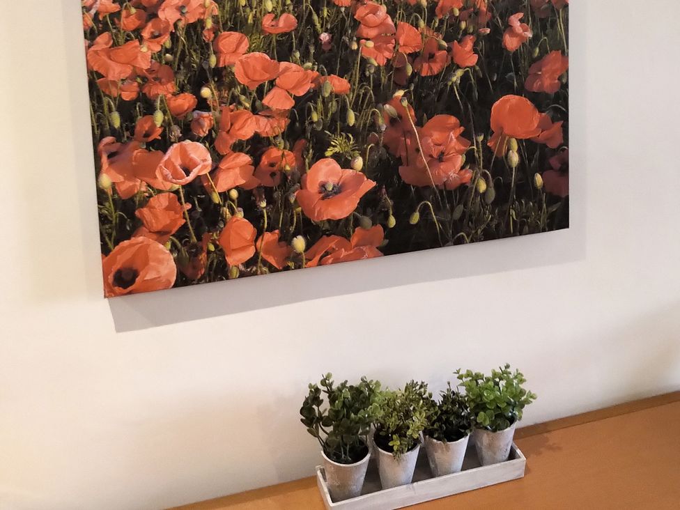 A table with potted plants and a painting of poppies at Oliver Wests Apartment 4, Scarborough