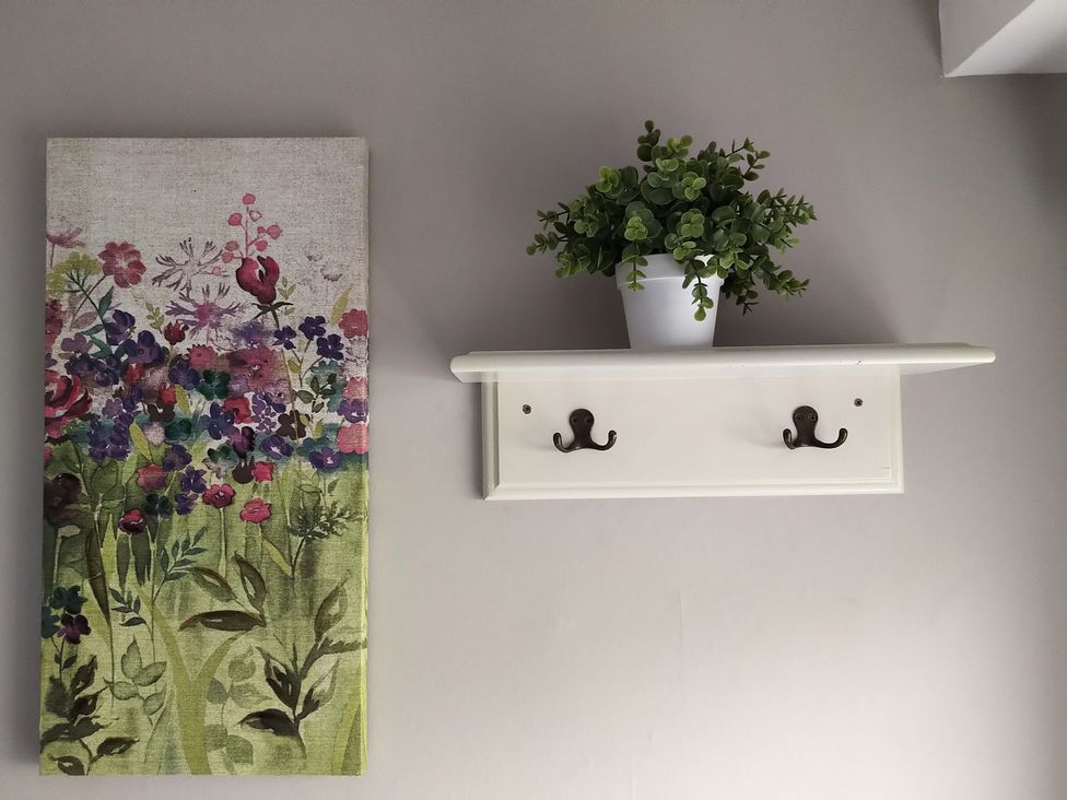 A shelf with a plant and hooks along with a painting at Oliver Wests Apartment 4 in Scarborough