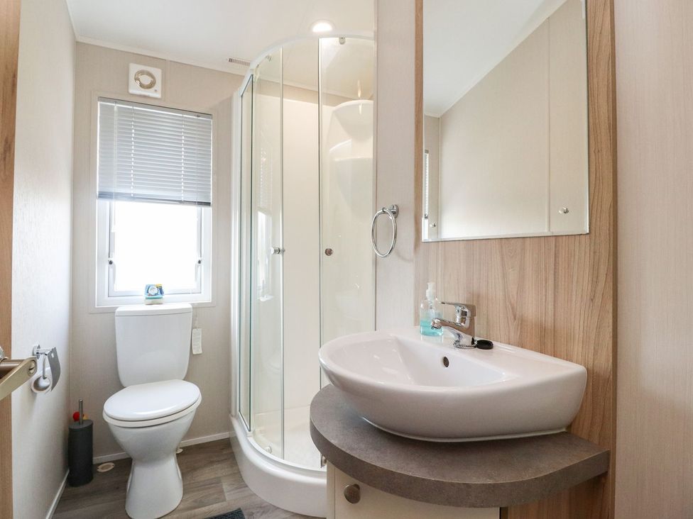 A bathroom with a toilet, sink, shower and a window at Rosella 38 Morecambe