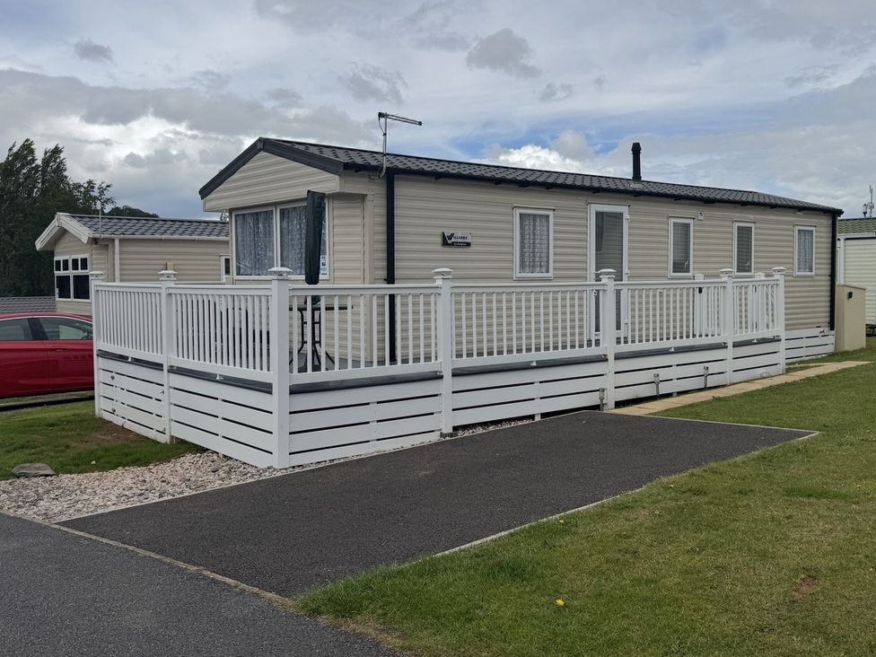 A mobile home with a deck and fence at Golden Sands Holiday Park in Dawlish