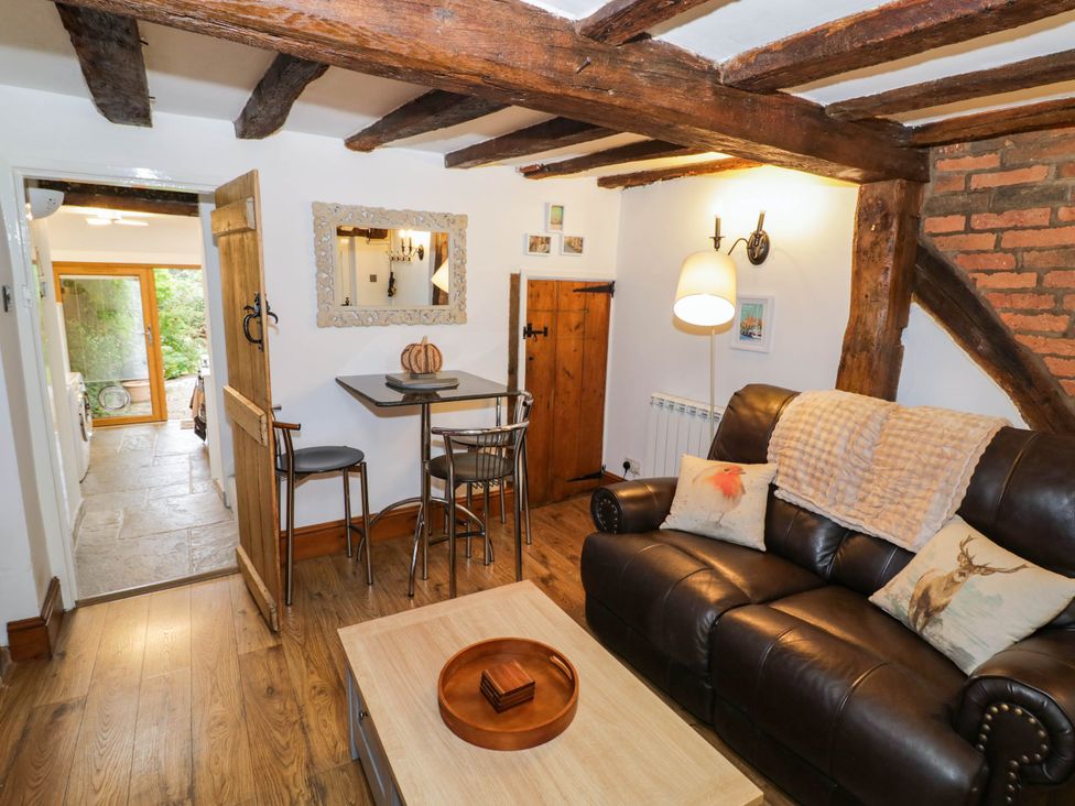 A living room with a sofa, table, and chairs at Lilac Cottage in Brinklow