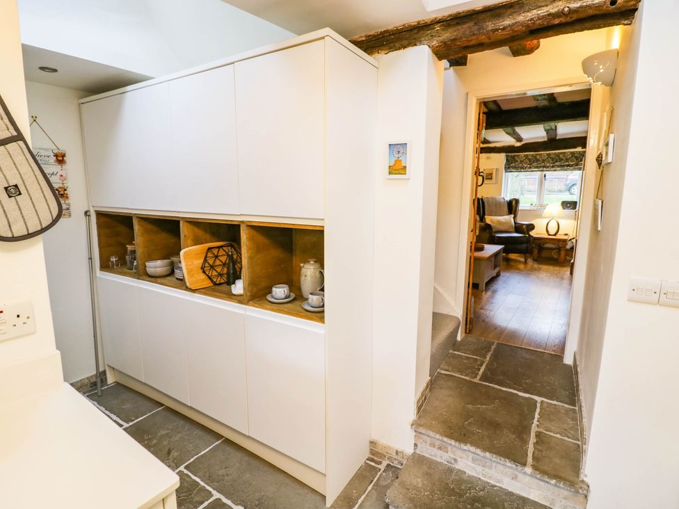 A kitchen with storage unit and mugs at Lilac Cottage in Brinklow