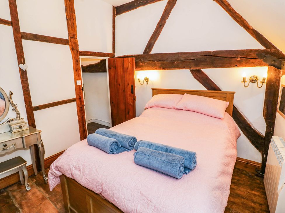 A bedroom with a bed and two towels at Lilac Cottage in Brinklow