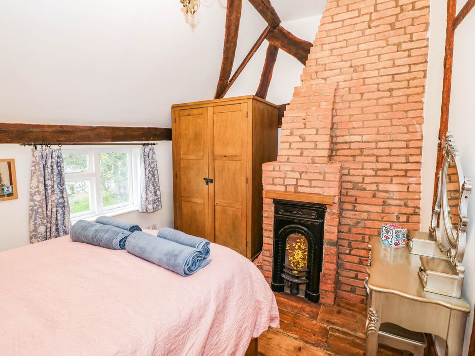 A bedroom with a bed and wardrobe at Lilac Cottage in Brinklow