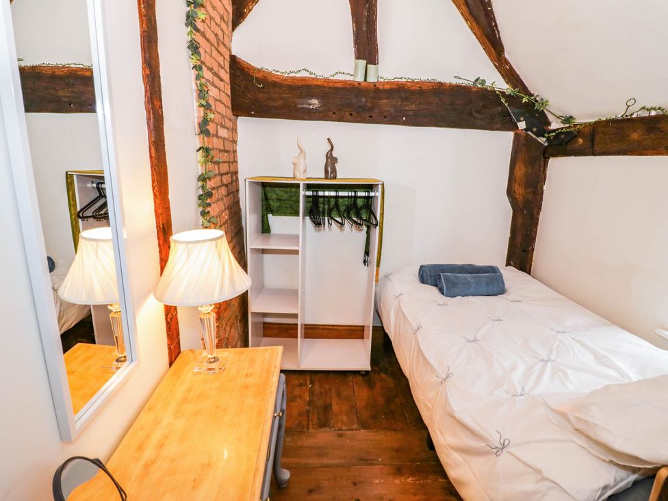 A bedroom with a bed and a wardrobe at Lilac Cottage in Brinklow