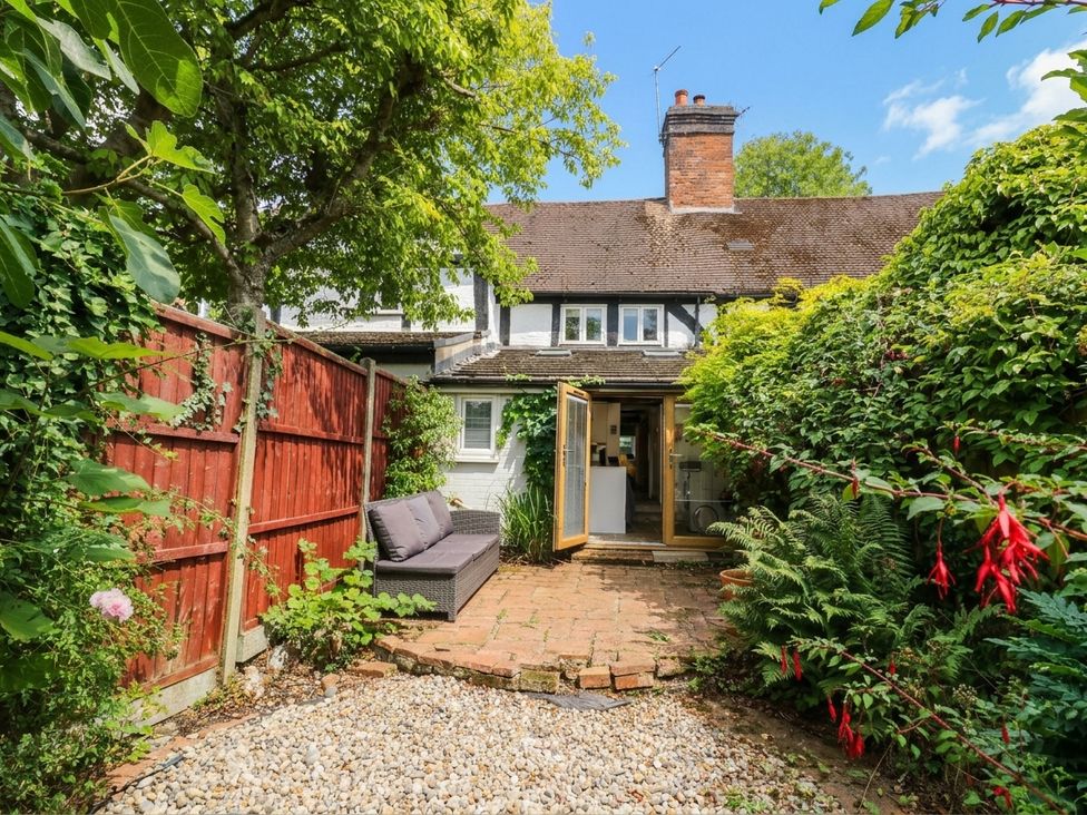 A garden with seating area and view of a house at Lilac Cottage in Brinklow